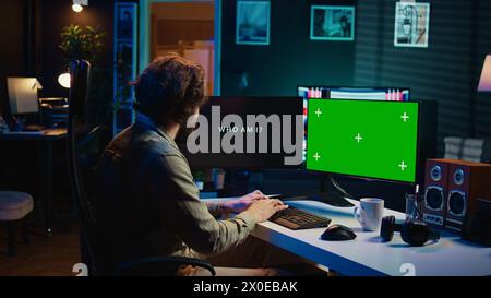 Programmatore che aggiorna l'algoritmo di intelligenza artificiale utilizzando un PC con schermo verde, rendendolo senziente. Specialista IT che programma l'intelligenza artificiale autoconsapevole con computer mockup, telecamera B. Foto Stock