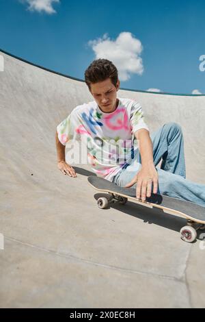 Un giovane skater che tiene in mano lo skateboard sulla rampa dello skate Park in una giornata estiva di sole. Foto Stock