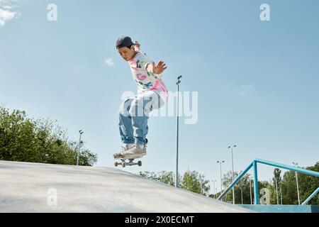 Un giovane skater cavalca con sicurezza il suo skateboard su un lato di una rampa in uno skate Park all'aperto in una giornata di sole. Foto Stock