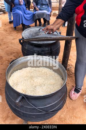 pentola di riso bollente in una pentola a tre zampe, cucina all'aperto, villaggio africano Foto Stock