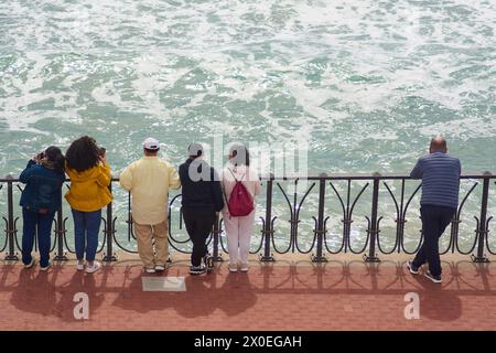 Tarragona, Spagna - 11 aprile 2024: Persone di età diverse a Tarragona osservano le onde del mare da una ringhiera, creando un relax e un disprezzo Foto Stock