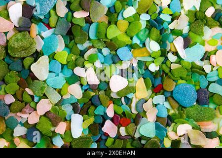 Frammenti multicolori di bottiglie di vetro lucidate dal mare sparse sullo sfondo Foto Stock