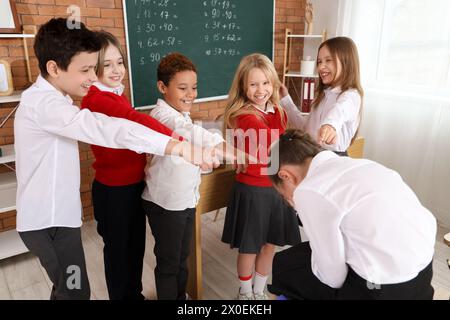 Bambini piccoli che fanno bullismo al loro compagno di classe in classe Foto Stock