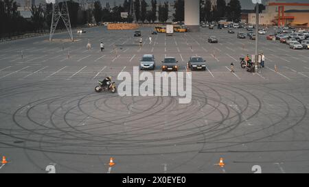 Il motociclista professionista fa acrobazie in bicicletta. Motociclista uomo motociclista estremo su una ruota. Trucco in moto. Stile di vita Motorsport. Parcheggio auto. Kiev, Ucraina, Europa. Ripresa cinematografica con drone Foto Stock