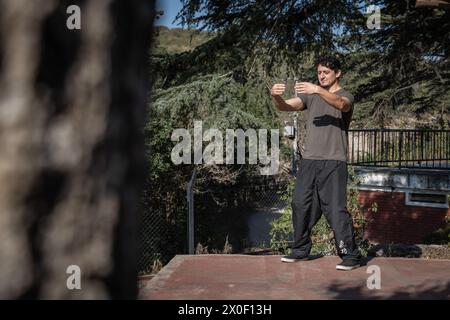 Vista distante di un uomo concentrato che pratica chi Kung con gli occhi chiusi nella postura abbracciante l'albero. Foto Stock