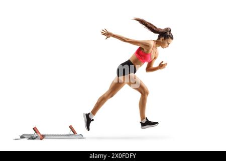 Foto a tutta lunghezza di un'atleta che inizia una gara con blocco di partenza isolato su sfondo bianco Foto Stock