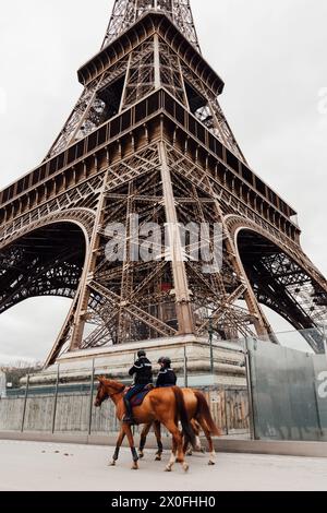 Coppia di polizia in cavalli che pattuglia la Torre Eiffel. Foto Stock