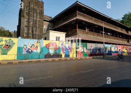 Una lunga parete a Mumbai, India, situata di fronte ad un edificio storico e decorata con colorati murales a tema Covid-19 Foto Stock