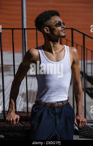 Un ragazzo rilassato e felice che si appoggia al corrimano al sole. Foto Stock