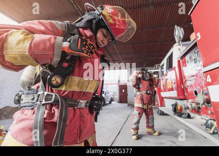 Vigile del fuoco con abbigliamento da lavoro che lavora al motore antincendio Foto Stock