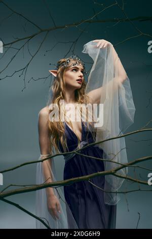 Una giovane donna trasuda vibrazioni fatate e fantasiose, vestita con un bellissimo abito blu con un delicato velo bianco. Foto Stock