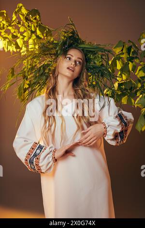 Una giovane donna, adornata con abiti tradizionali, abbellisce lo studio con un abito bianco decorato, simile a una fiaba, con capelli lunghi e fluenti. Foto Stock