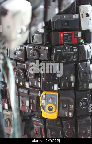 Vecchie telecamere a pellicola impilate e trasformate in una figura umana che mostra rifiuti elettronici o rifiuti elettronici che di solito vanno in discarica Foto Stock
