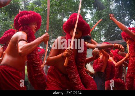 Munshiganj, Dacca, Bangladesh. 12 aprile 2024. I devoti indù hanno preso parte al festival annuale Lal Kach (vetro rosso) a Munshiganj, Bangladesh. Durante il festival Hindu Lal Kach, bambini e uomini si dipingono di colore rosso e partecipano a una processione con spade mentre mostrano il potere contro il male e accolgono il nuovo anno Bengalese. Il festival di Lal Kach è ben noto per la comunità locale da più di cento anni. Credito fotografico: ZUMA Press/Alamy Live News Foto Stock