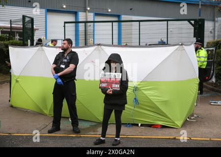 Un manifestante regge un cartello che dice "Dismandi la macchina della guerra - Spegni Elbit" mentre gli agenti di polizia lavorano per liberare un attivista da dietro uno schermo portatile fuori dalla fabbrica di Elbitís. Due attivisti della Palestine Action guidano due auto nei dissuasori ai cancelli della fabbrica di Elbitís e si chiudono al volante con un D-lock intorno al collo per impedire ai lavoratori di entrare nel sito. La fabbrica Unmanned Aerial Vehicle Tactical System (UTACS) è di proprietà della compagnia israeliana Elbit Systems. È uno dei sette stabilimenti che Elbit ha nel Regno Unito producendo armi e droni per l'Isra Foto Stock