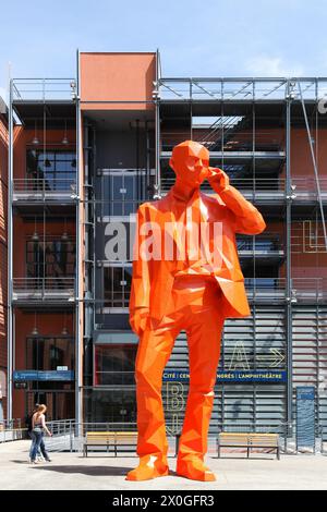 Lione, Francia - 28 maggio 2015: La Cité internationale di Lione con la statua arancione dell'uomo d'affari nella piazza dell'anfiteatro Foto Stock