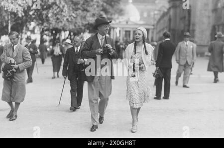 Un uomo più anziano e una ragazza più giovane stanno camminando lungo una strada con le loro macchine fotografiche. (registrazione non datata) [traduzione automatica] Foto Stock