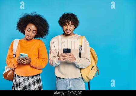 Una coppia multiculturale di studenti affiancati a smartphone in uno studio, che mostra unità e amicizia. Foto Stock