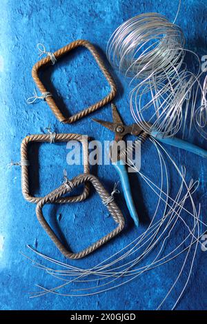 Pinze vintage, filo e acciaio di rinforzo su sfondo blu testurizzato con spazio di copia. Lavori di ristrutturazione della casa nei dettagli. Foto Stock