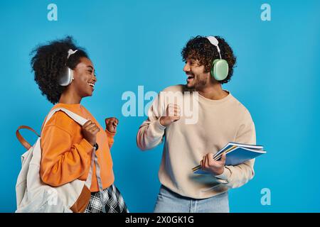 Un uomo e una donna interrazziali in piedi con sicurezza in un abbigliamento casual su uno sfondo blu. Foto Stock