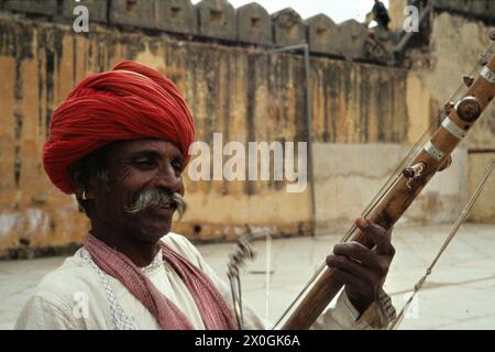Un anziano con un turbante rosso gioca un sitar nel cortile del palazzo in ambra. [traduzione automatica] Foto Stock
