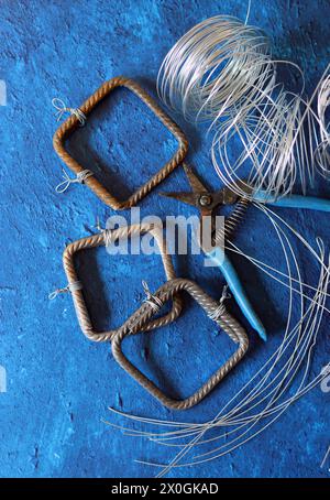 Pinze vintage, filo e acciaio di rinforzo su sfondo blu testurizzato con spazio di copia. Lavori di ristrutturazione della casa nei dettagli. Foto Stock