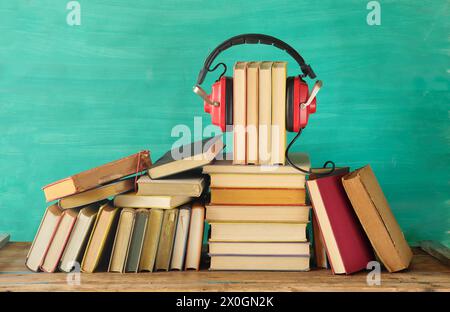Ampia raccolta di libri e afoni, concetto di audiolibri, intrattenimento, istruzione e e-learning su sfondo verde acqua, spazio di copia gratuito. Foto Stock
