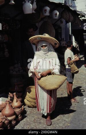 Un'anziana donna marocchina con velo, cappello e cesto della spesa nella medina (città vecchia) di Tetuan. [traduzione automatica] Foto Stock