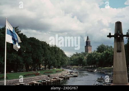 Bandiera finlandese davanti all'Aurajoki a Turku con la Cattedrale di Turku sullo sfondo. [traduzione automatica] Foto Stock