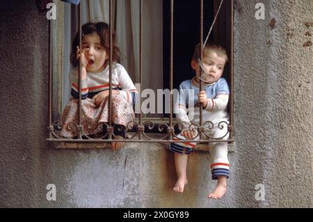 Due bambini sono seduti su una davanzale nel quartiere della città vecchia di Eminönu a Istanbul. La finestra è barrata. [traduzione automatica] Foto Stock