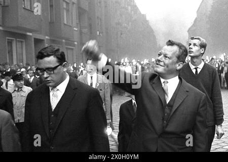 Il sindaco di Berlino Ovest Willy Brandt alza la mano accanto a Klaus Schütz durante una manifestazione a Kreuzberg per celebrare il primo anniversario della costruzione del muro di Berlino. [traduzione automatizzata] Foto Stock