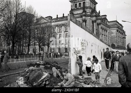 I bambini giocano nei resti e nelle rovine del Muro di Berlino presso l'edificio del Reichstag. [traduzione automatica] Foto Stock