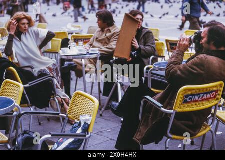 Un post modello in un cafÃ© su St. Piazza Marco. Il fotografo lavora con concentrazione, il suo assistente piuttosto annoiato illumina la scena. [traduzione automatizzata] Foto Stock