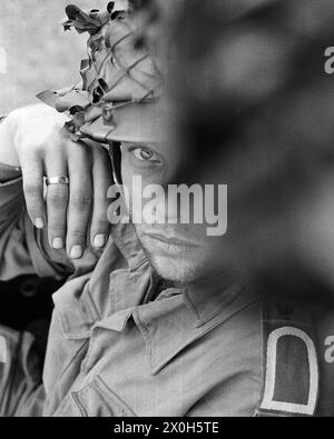 Durante un esercizio militare del II corpo delle forze armate tedesche nell'Alb svevo, un sergente di stato maggiore in uniforme attende di essere schierato. Il suo volto è parzialmente coperto, indossa una tuta da campo, un casco da combattimento e la sua fede nuziale. [traduzione automatizzata] Foto Stock