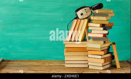 Ampia raccolta di libri e afoni, concetto di audiolibri, intrattenimento, istruzione e e-learning su sfondo verde acqua, spazio di copia gratuito. Foto Stock
