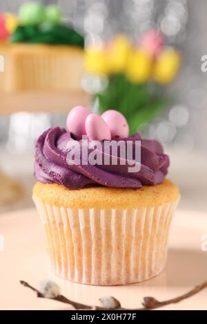 Gustoso cupcake pasquale con panna luminosa sul tavolo, primo piano Foto Stock