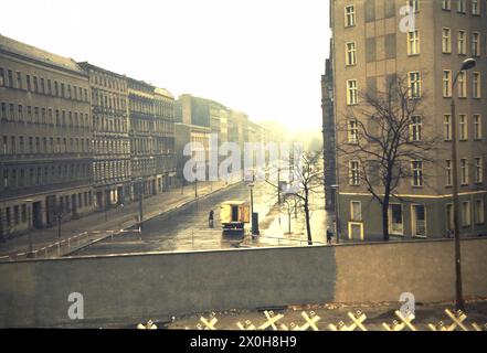 Una gita scolastica a Berlino era comune all'epoca. Per me, è stato anche un viaggio nella memoria. La vista spazia su una piattaforma in Bernauerstrasse in una strada laterale. Il muro raffigurato è già il secondo muro, il muro esterno, e si affaccia su Berlino Est. Potete vedere questo perché le barriere anticarro sono state posizionate tra le due pareti. Scene strazianti ebbero luogo qui dopo il 13 agosto 1961. Per fare spazio alle fortificazioni di confine e alla striscia di morte e per evitare fughe, l'intera facciata di Berlino Est fu demolita. I fumi di zolfo si notano più avanti si guarda verso est Foto Stock