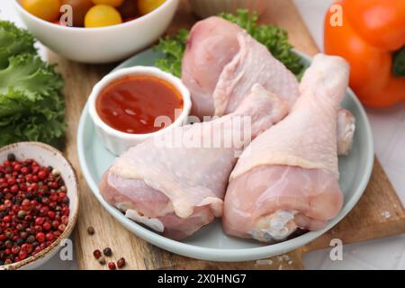 Marinata fresca, cosce di pollo crudo e altri prodotti in tavola, primo piano Foto Stock