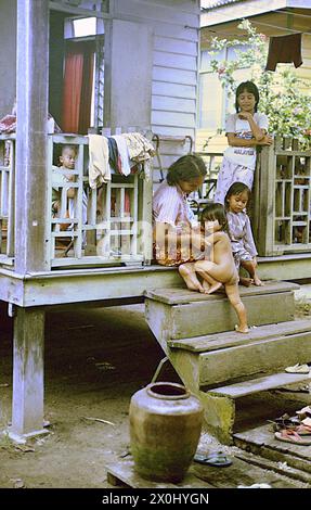 Una madre siede con i suoi figli sulle scale di fronte alla sua casa. [traduzione automatica] Foto Stock