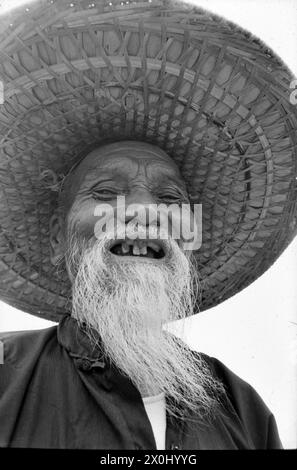 Il ritratto eines alten Manns mit langem Weißen Bart und Strohhut a Hong Kong. Er lacht. IHM fehlen einige Zähne. (Aufnahmedatum: 01.08.1974-31.08.1974) Foto Stock