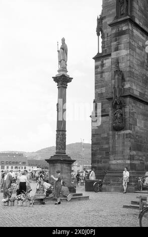 "Al centro si trova una delle tre colonne patronali, a destra si trova una parte della torre della cattedrale di Friburgo con la statua ""conte di Friburgo con spada giudiziaria"". Visitatori e bancarelle del mercato della cattedrale sulla piazza. [traduzione automatizzata]' Foto Stock