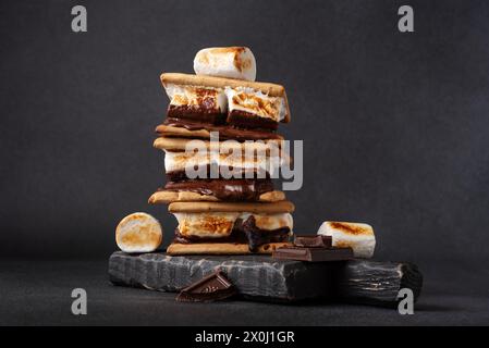 smores appena tostati. Delizioso sandwich al marshmallow con cracker e cioccolato su sfondo scuro. Foto Stock