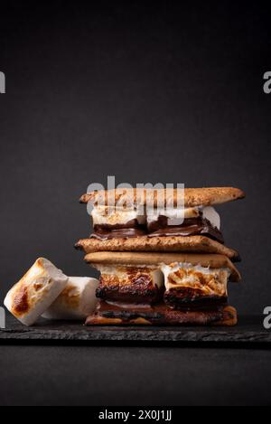 smores appena tostati. Delizioso sandwich al marshmallow con cracker e cioccolato su sfondo scuro. Foto Stock