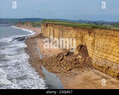 Burton Bradstock, Dorset, Regno Unito. 12 aprile 2024. Meteo nel Regno Unito. Vista aerea dell'ultima enorme cascata rocciosa sulla Jurassic Coast a Hive Beach a Burton Bradstock nel Dorset durante un caldo pomeriggio di sole. La caduta di roccia avvenuta il 9 aprile 2024 è l'ultima di una serie di scogliere che crollano lungo le scogliere di arenaria tra West Bay e Burton Bradstock durante l'inverno e la primavera dopo ripetute tempeste e forti piogge hanno colpito la costa. Credito fotografico: Graham Hunt/Alamy Live News Foto Stock