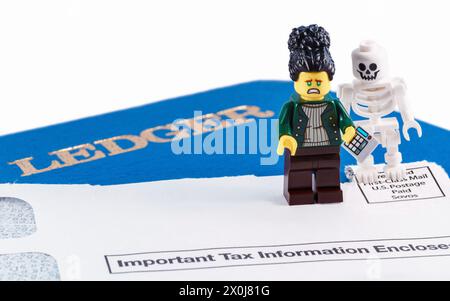Chappaqua, NY - 11 aprile 2024: LEGO minifigures ragioniere e scheletro illustrazione umoristica di dire, nulla è certo tranne morte e tasse. Foto Stock