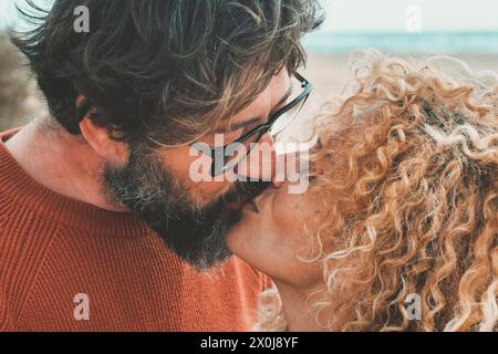 Persone adulte, uomo e donna innamorati e in relazione, baciati sulla spiaggia con il mare sullo sfondo. Le coppie che hanno un rapporto felice hanno un soggiorno romantico e piacevole, con tenerezza e bacio Foto Stock