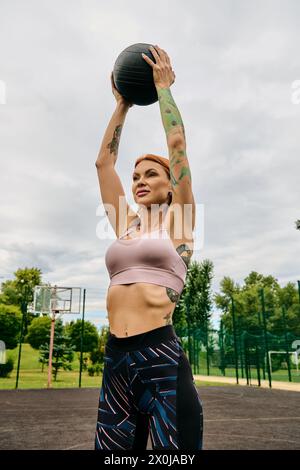Una donna in abbigliamento sportivo, che tiene una palla medica, si allena all'aperto Foto Stock