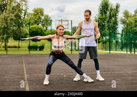 Un uomo e una donna in abbigliamento sportivo sono in piedi su un campo da tennis, concentrandosi sul loro allenamento con determinazione e motivazione. Foto Stock