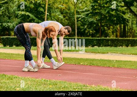 Un uomo e una donna, vestiti di abbigliamento sportivo, si allenano insieme su una pista, mostrando determinazione e motivazione. Foto Stock