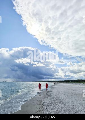 Due persone camminano lungo il bordo dell'acqua sulla spiaggia di Prerow, Meclemburgo-Vorpommern, Germania Foto Stock